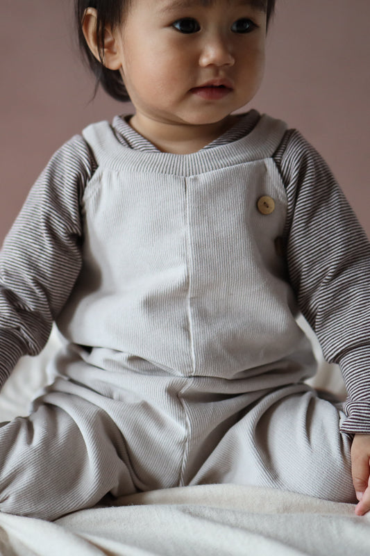 Rückansicht der Latzhose Feincord - Sand, stilvoll und funktional für aktive Kinder.
