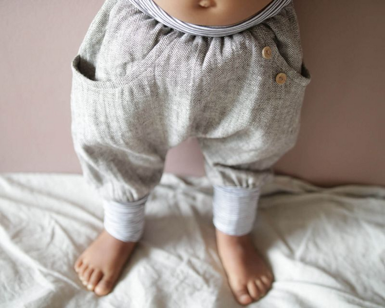 Nahaufnahme von Babybeinen in einer Knickerbocker Fischgrat von Petit Cochon. Geeignet für Babys und Kleinkinderkleidung.