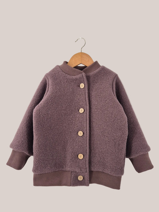 Bomberjacke Wollwalk - Malve, eine Kinderjacke aus Wollwalk mit Knöpfen, auf einem Bügel hängend, zeigt Details wie braune Strickärmel und Holzknöpfe.