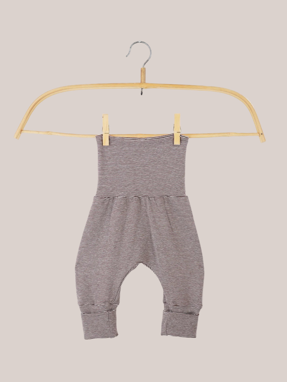 Babyknicker Bio-Baumwolle - Schoko Ringel, nahaufnahme zeigt weiche, atmungsaktive Streifenhose auf einem Haken mit Holzgriff, betont Bewegungsfreiheit und Komfort für zarte Babyhaut, nachhaltig hergestellt in Berlin.