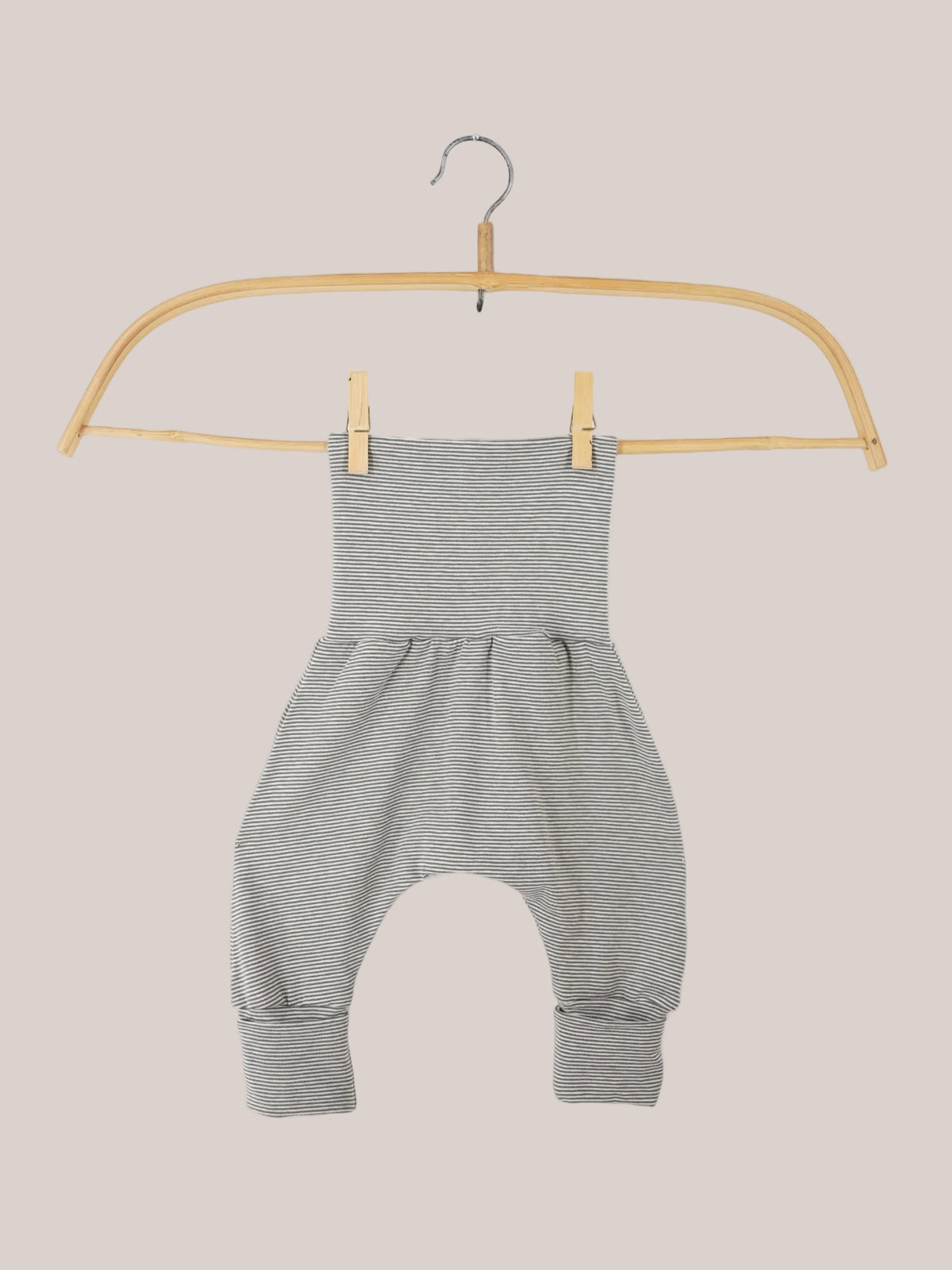 Babyknicker Bio-Baumwolle - Maus Ringel: Nahaufnahme eines grau-weiß gestreiften Rompers auf einem Kleiderbügel mit Holzgriff, zeigt den weichen, luftigen Schnitt für Bewegungsfreiheit und Komfort.