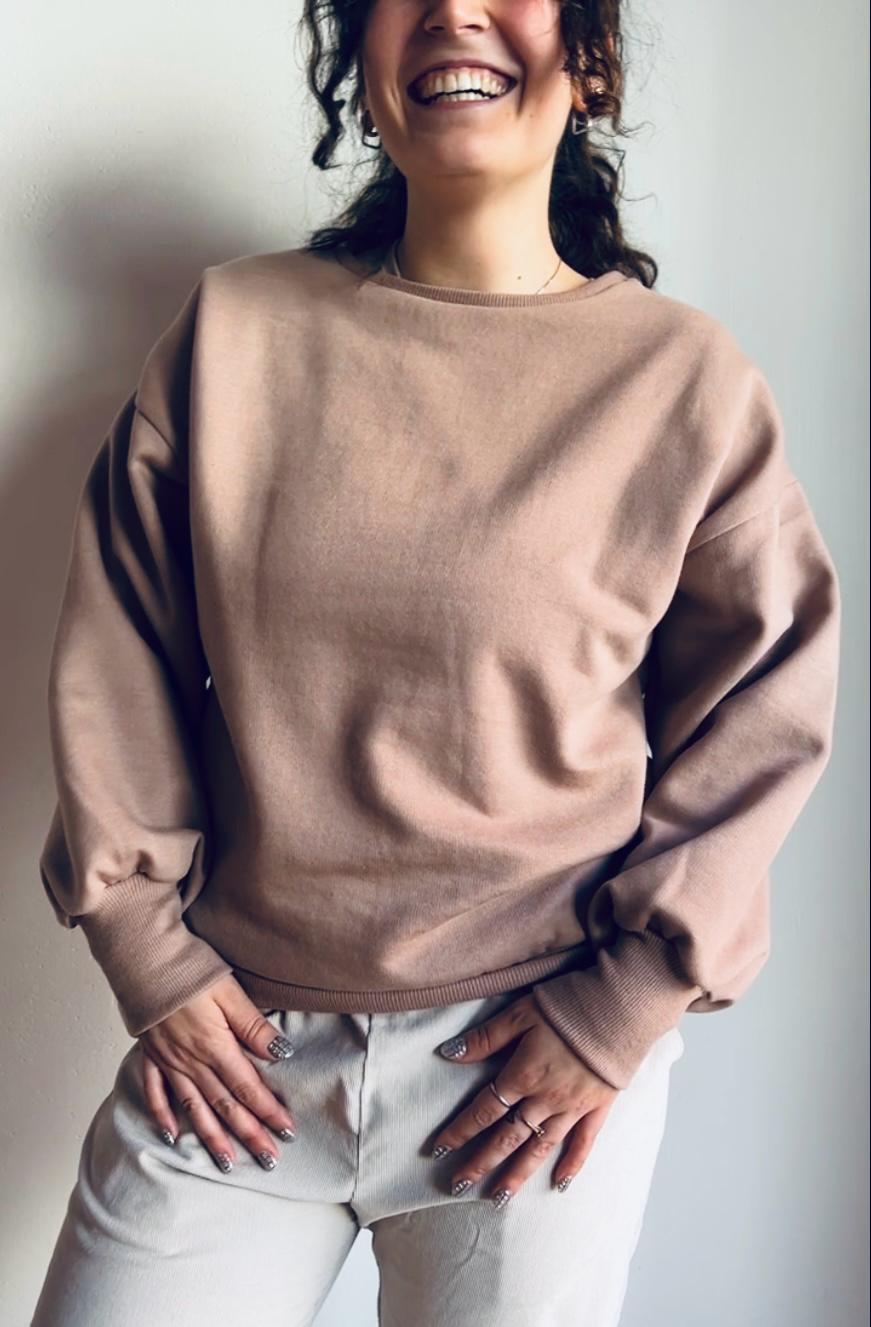 Mujer con suéter Pumppulli de mujer de corte holgado, confeccionado en algodón orgánico, en color polvo, con hombros caídos, informal y atemporal, ideal para el día a día y para lucir con estilo. Perfecto para llevar a juego en pareja.