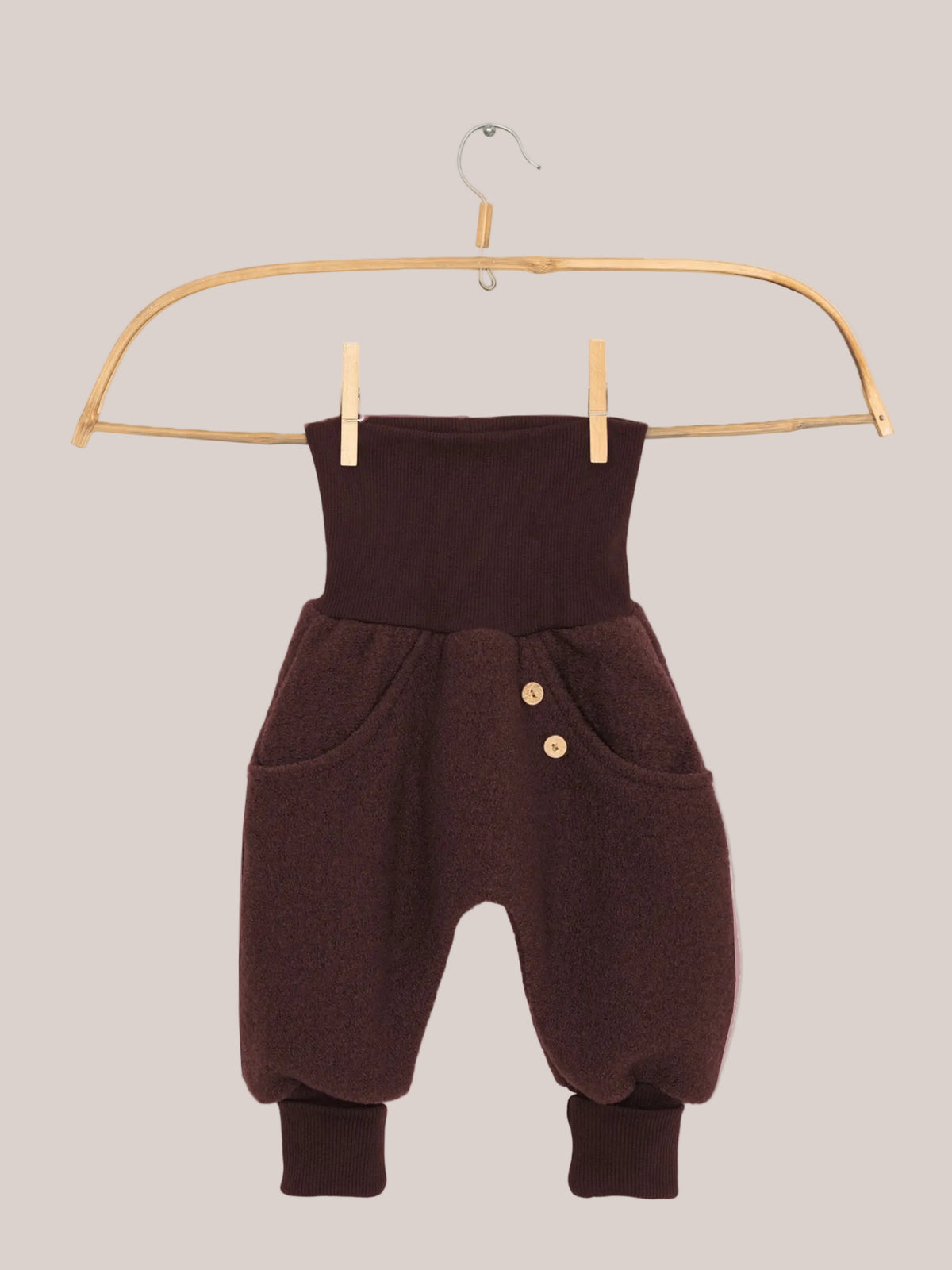 Knickerbocker Wollwalk - Schoko: Kleine haremartige Hose mit hohem, geripptem Bund, Seitentaschen mit Holzknöpfen, flauschigem Wollstoff, und gerippten Knöchelbündchen, hängt an einem Holzkleiderbügel.
