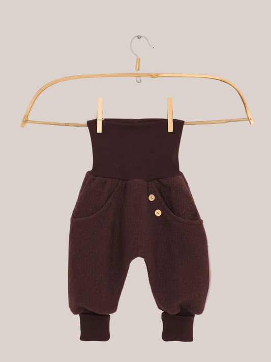 Knickerbocker Wollwalk - Schoko: Kleine haremartige Hose mit hohem, geripptem Bund, Seitentaschen mit Holzknöpfen, flauschigem Wollstoff, und gerippten Knöchelbündchen, hängt an einem Holzkleiderbügel.