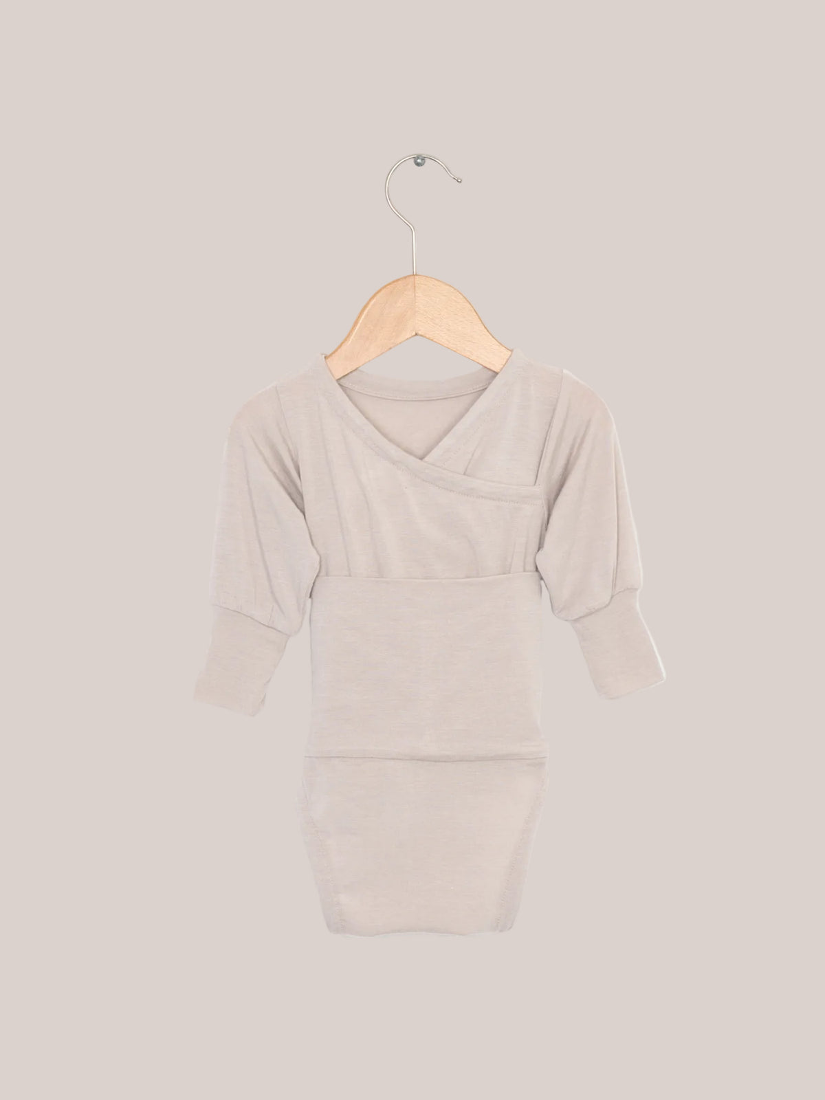Loopbody Kaschmir-Mix - Sand: Ein babybody ohne Knöpfe auf einem Holzkleiderbügel. Der weiche, langärmelige Body hat einen speziellen Loop zum einfachen Anziehen und bietet extra Wärme.  Erstausstattung Baby und Baby Geschenk zur Geburt.