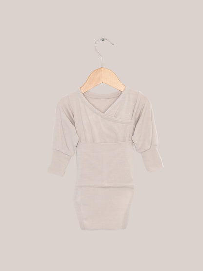 Loopbody Kaschmir-Mix - Sand: Ein babybody ohne Knöpfe auf einem Holzkleiderbügel. Der weiche, langärmelige Body hat einen speziellen Loop zum einfachen Anziehen und bietet extra Wärme.  Erstausstattung Baby und Baby Geschenk zur Geburt.