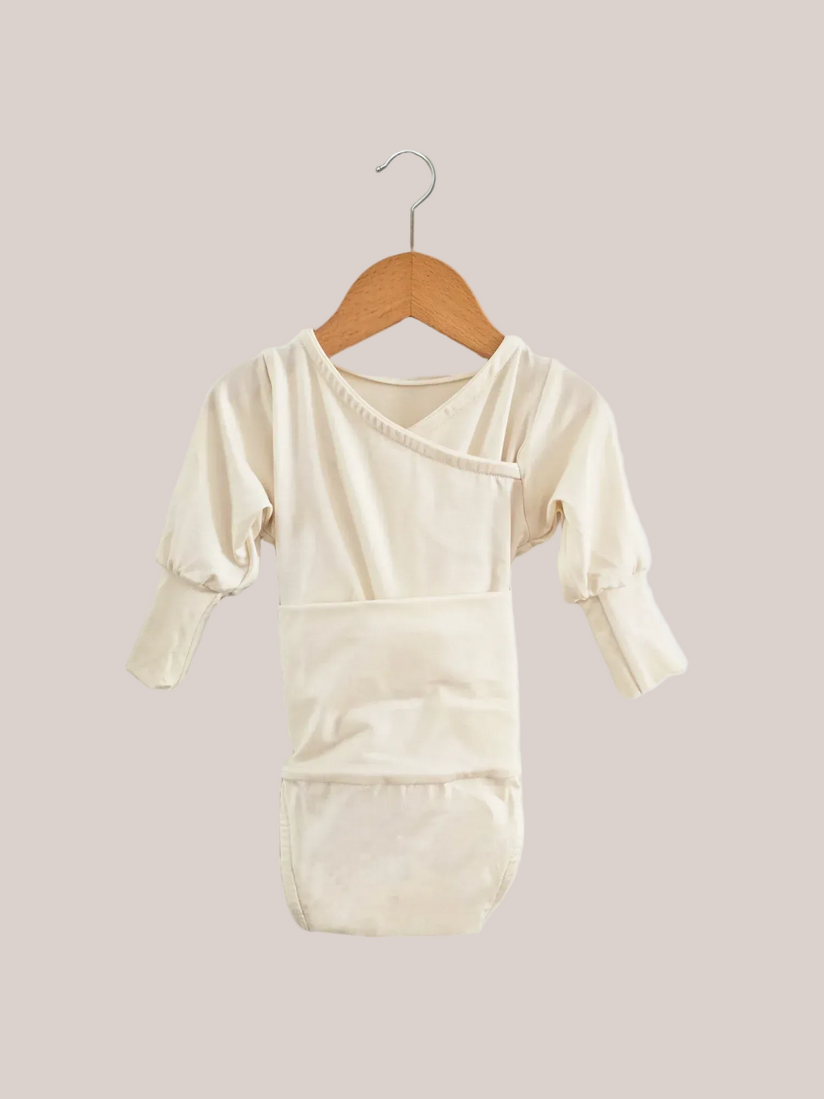 Loopbody in viscosa di bambù – Naturale: stile kimono, maniche lunghe, fascia addominale integrata, chiusura a portafoglio senza bottoni. Appeso a una gruccia di legno, progettato per il comfort e per adattarsi alla crescita del bambino.
