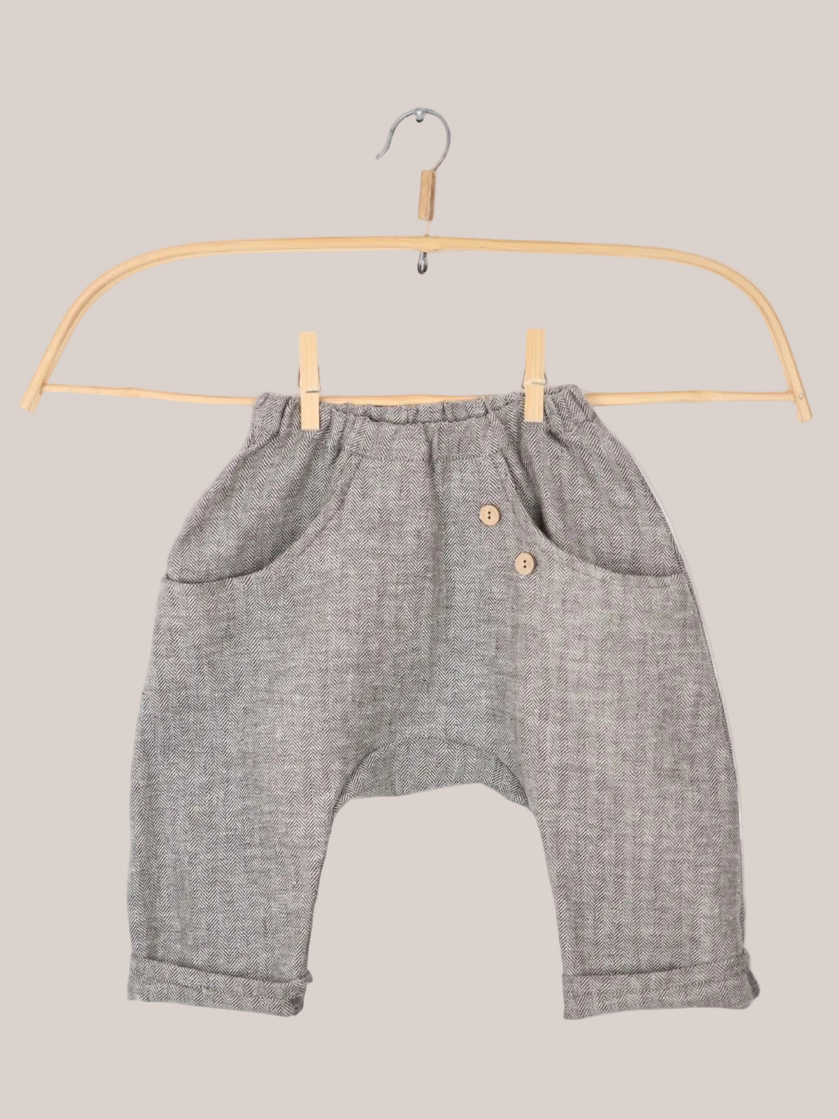 Pantalones de verano de espiga, talla: primer plano que muestra un gancho y un par de pantalones en un tendedero; las mangas son más cortas que en un corte normal, aproximadamente de 3/4 de largo.