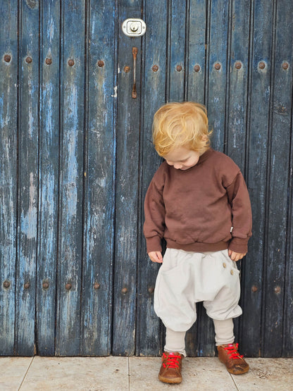 Tout-petit portant le pull en sweat bio – chocolat ; pull marron douillet en sweat bio doux. Coupe confortable, larges bordures côtelées, idéal au quotidien et pour jouer. Fabriqué à Berlin, durable et respirant.