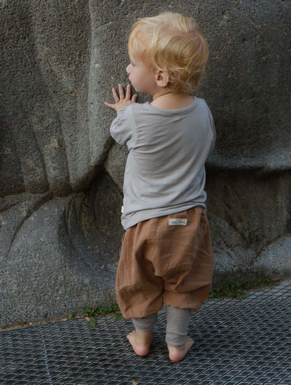 Nahaufnahme eines Wickelshirt aus Kaschmir-Mix - Sand, das weichen, elastischen Stoff zeigt. Geeignet für Kleinkinder, mit krempelbaren Bündchen, handgenäht in Berlin, ideal als Shirt oder Unterhemd.