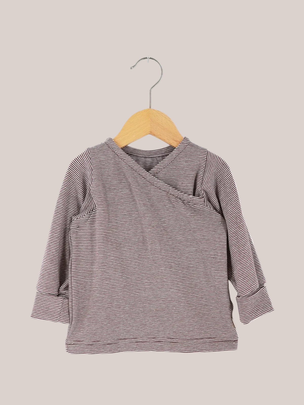 Organic cotton wrap shirt – Chocolate stripe, long-sleeved, with a wrap-style front and roll-up cuffs, hanging on a wooden hanger. Perfect for babies, easy to put on, and designed to grow with them.