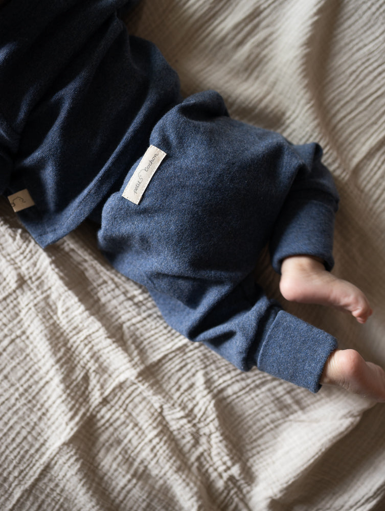 petit cochon Babyknicker aus blauem, meliertem Feinstrick-Jersey mit weichen Bündchen auf einer hellen Decke