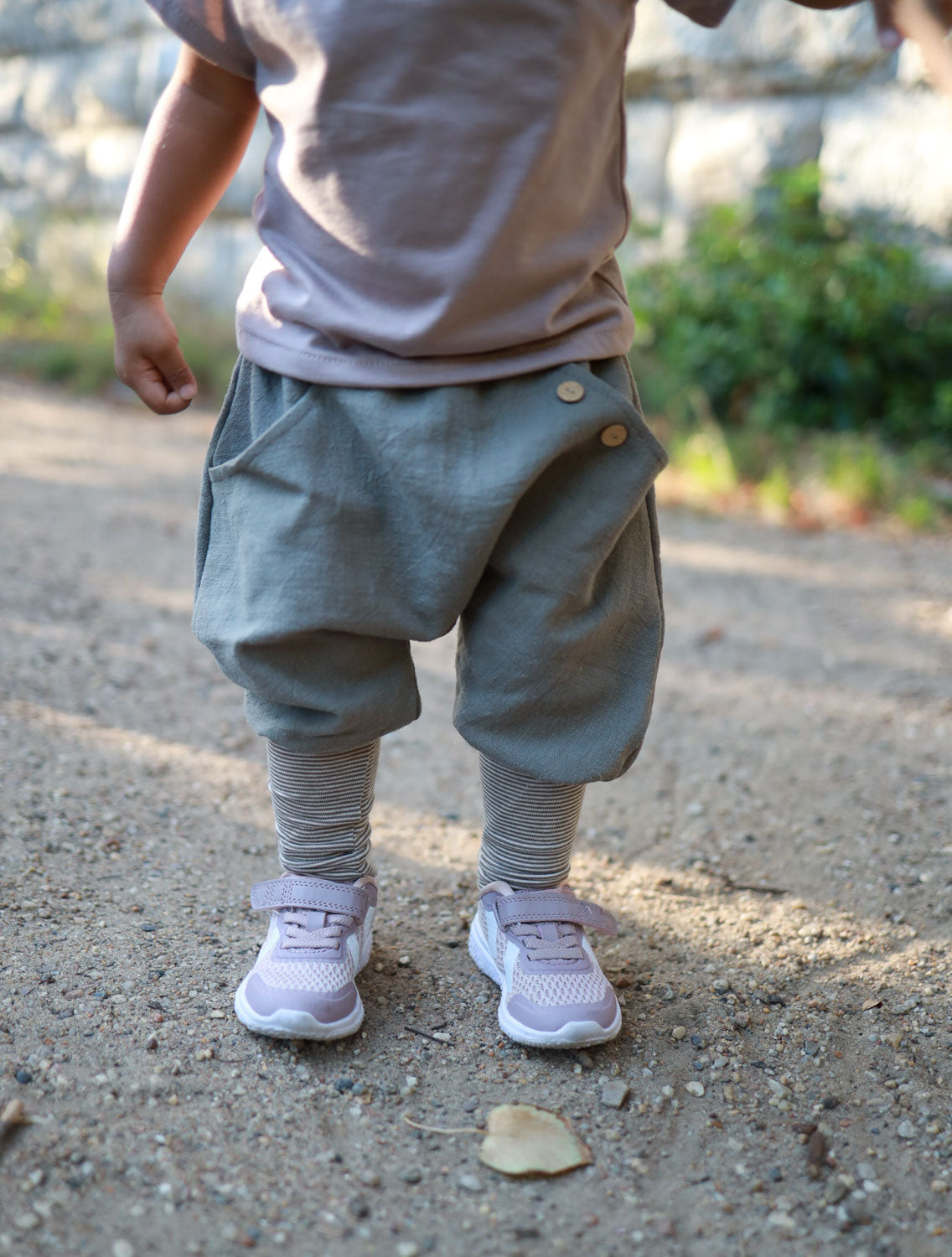 petit cochon Knickerbocker aus grauem Leinen mit mitwachsendem Bund an einem Kind im Freien