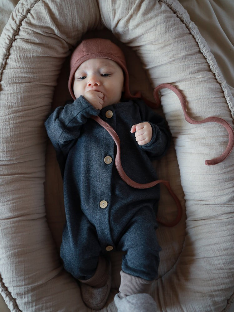 Baby in petit cochon Mini Overall aus dunkelgrauem, meliertem Feinstrick-Jersey mit Holzknöpfen im Babynest