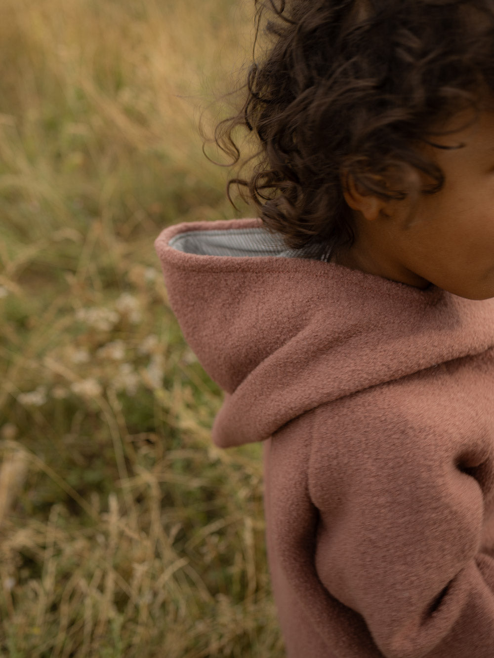 petit cochon Wichteljacke aus altrosa Wollwalk mit gestreiftem Bio-Jersey-Futter in der Kapuze bei einem Kind