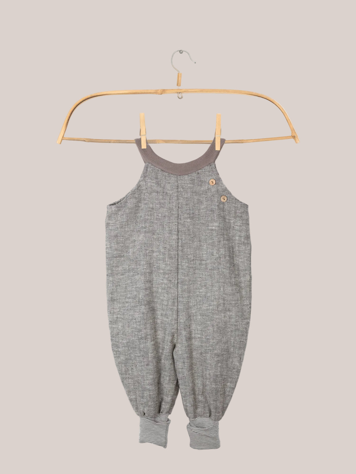 Schlupflatzhose aus Fischgrat auf einem Kleiderbügel, Sie zeigt das robuste Leinen-Baumwoll-Mix-Material und die umkrempelbaren Jerseybündchen, ideal für Kinderbewegungen.