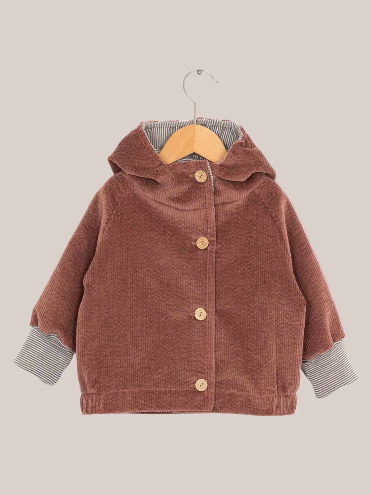Wichteljacke Breitcord - Rosenholz mit Ringelkapuze, krempelbaren Ringelarmbündchen und Knopfverschluss, auf einem Holzständer präsentiert, zeigt detailreiche Verarbeitung.